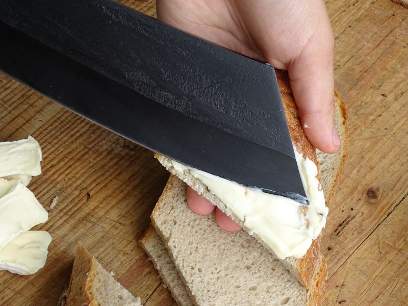 A úplný paradox – čtvrtka chleba mazaná zrajícím těžce roztíratelným sýrem, nožo-mačetou ze čtverky.